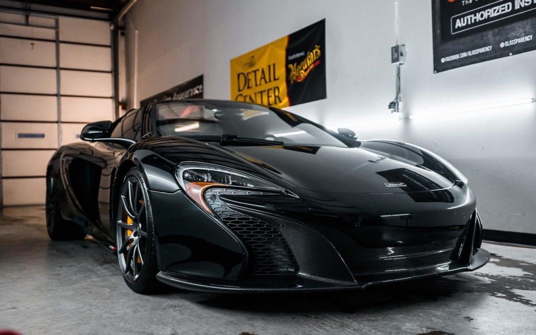A black sports car is parked in a garage.