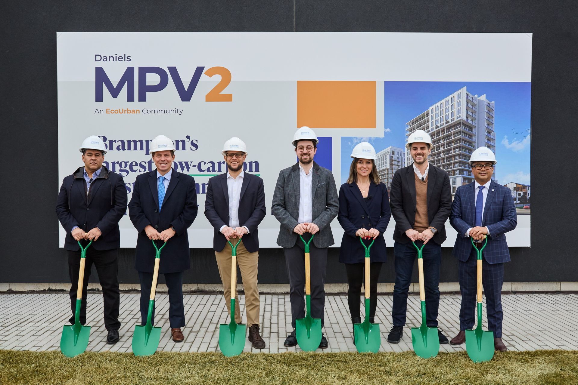 A group of people holding shovels in front of a sign that says mpv2.