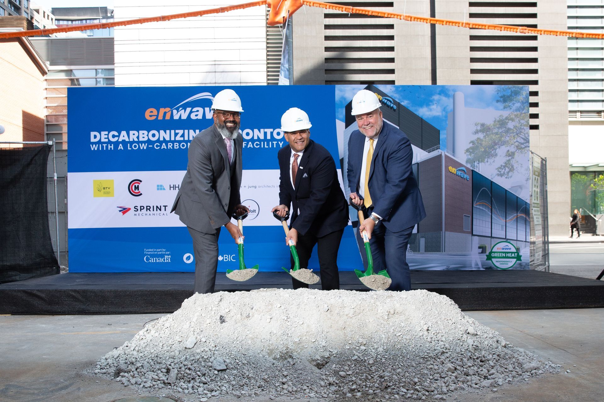 Three men wearing hard hats are digging a hole in the ground