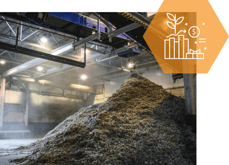 A pile of trash is being loaded into a conveyor belt in a factory.