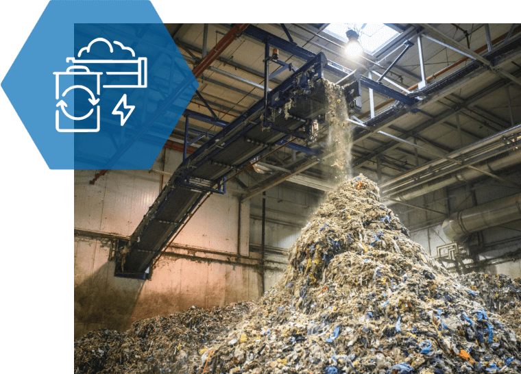 A pile of trash is being loaded into a conveyor belt in a factory.