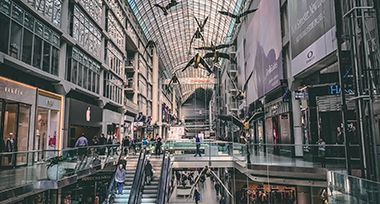 A large shopping mall with a lot of people walking down the stairs.