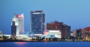 A city skyline at night with a large body of water in the foreground.