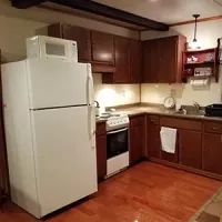 Small kitchen with white fridge, stove, wood cabinets, and hardwood floor.