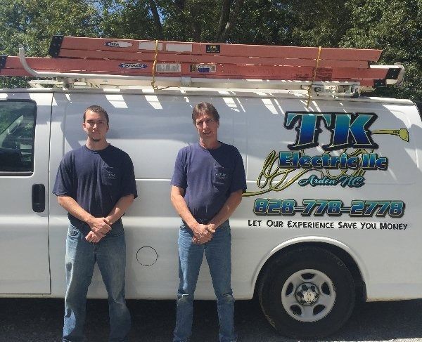 A gloved hand uses pliers to work on the wiring inside an open electrical terminal box.