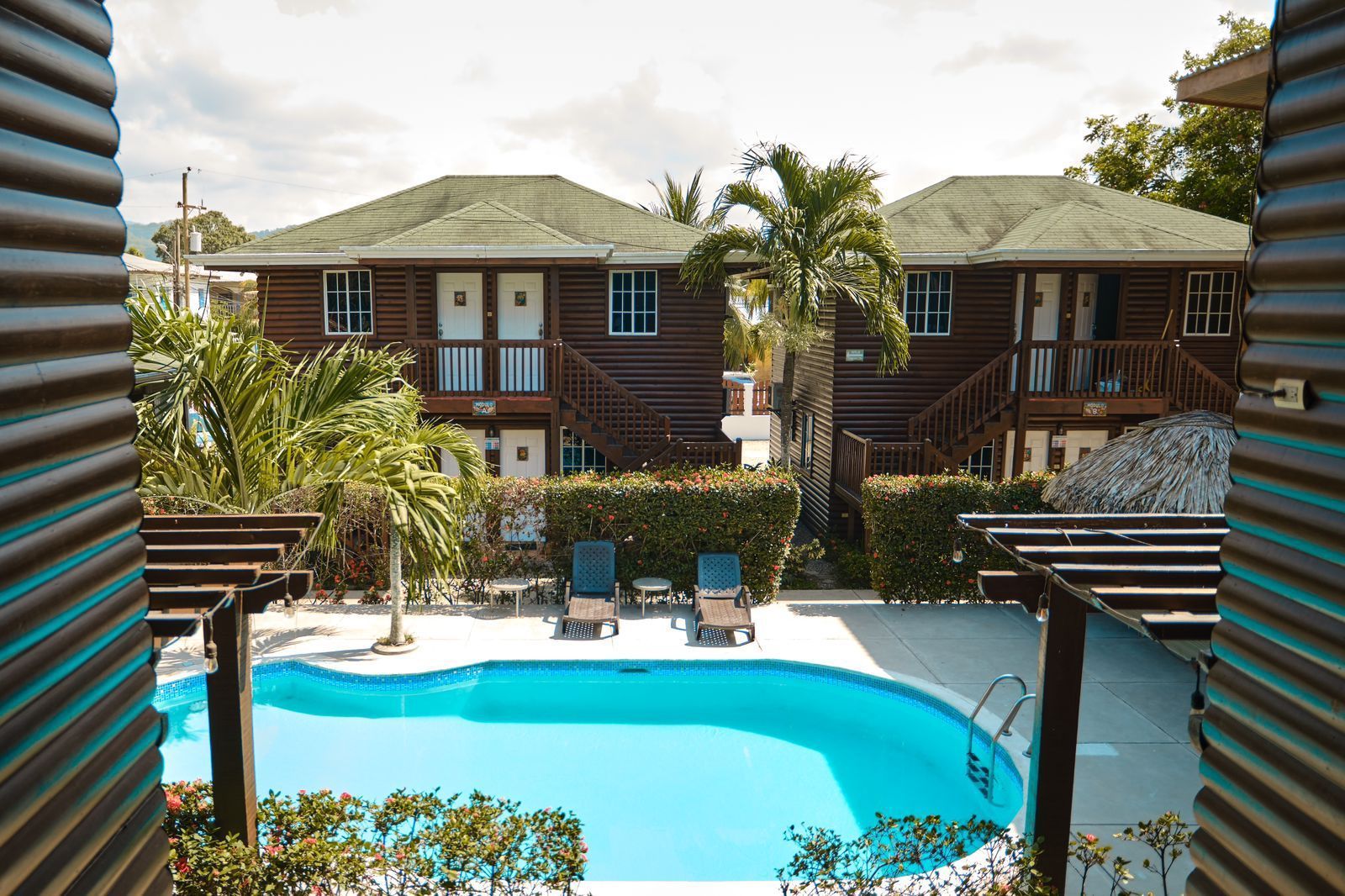 Piscina en patio de edificios de madera marrón con tumbonas.