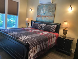 Dormitorio con cama negra, ropa de cama a cuadros y obras de arte de veleros.