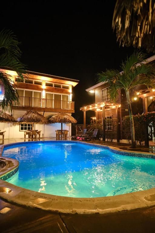 Una gran piscina se ilumina por la noche frente a un hotel.