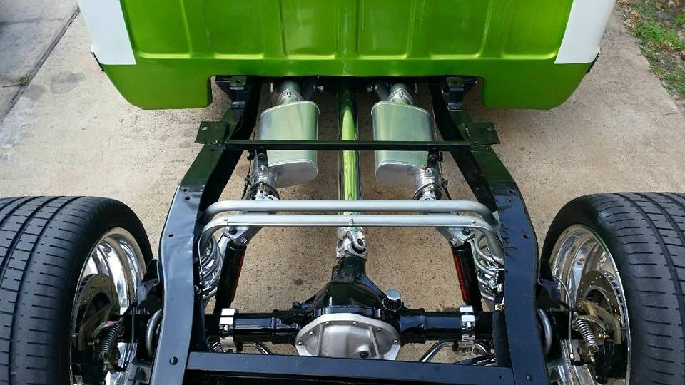 A classic, black pickup truck sits in front of a car repair shop.