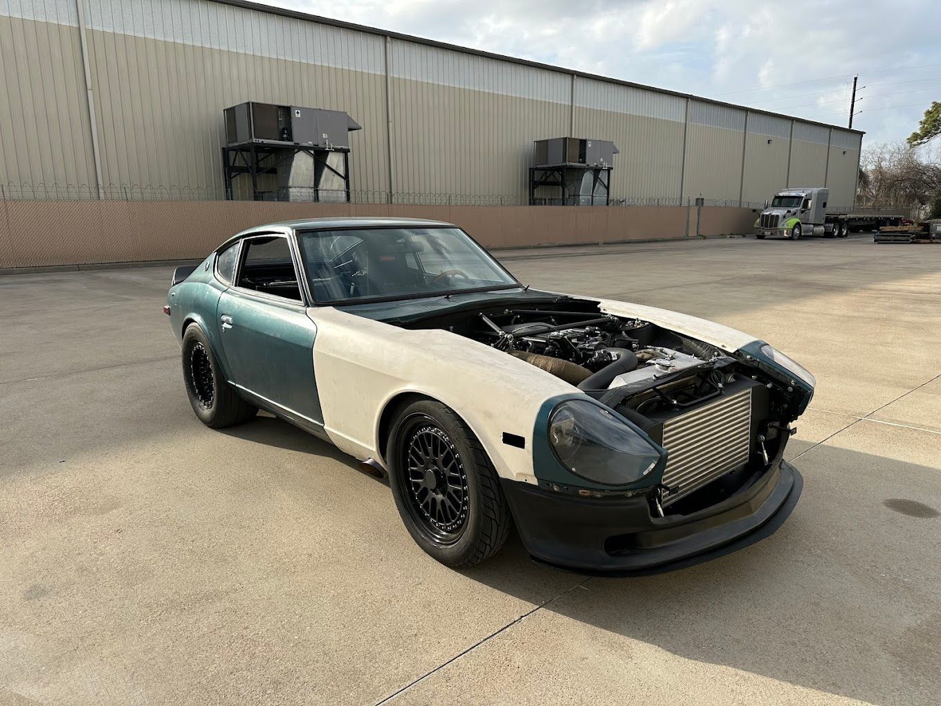 A classic, red sports car sits in an auto body shop.