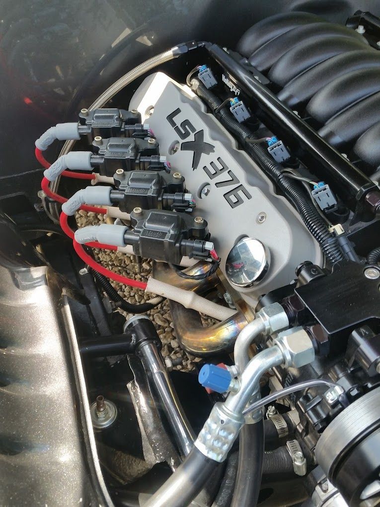 A car engine with visible ignition coils. Text on the engine reads LSX 376.