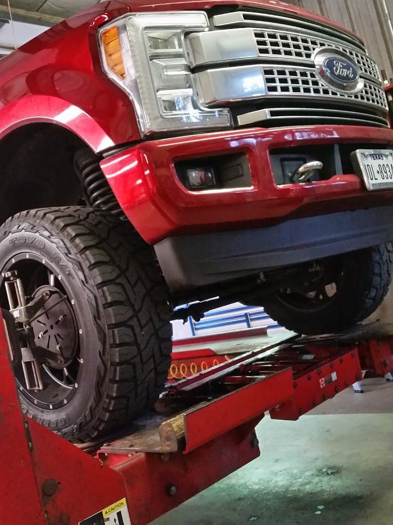 A red, Ford SUV is on a car lift.