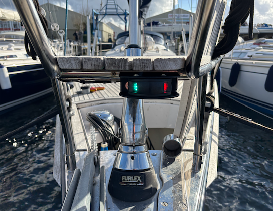 Een zeilboot ligt aangemeerd in een jachthaven met een rood en groen licht op de preekstoel