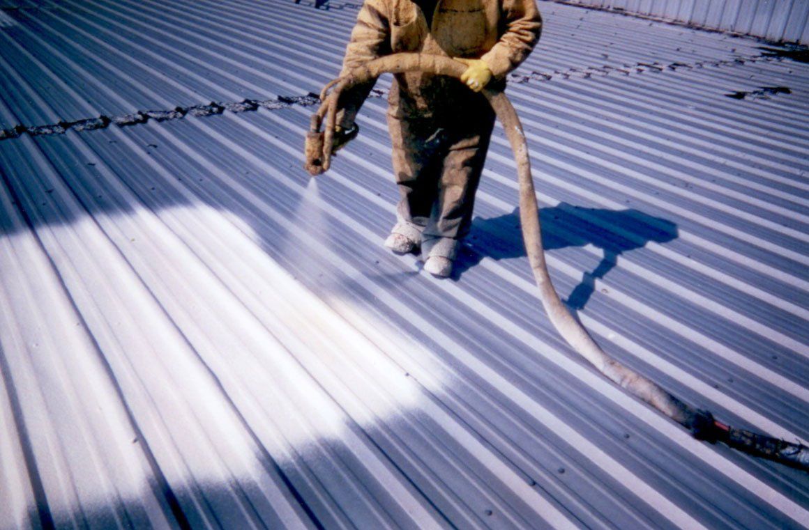man spraying roof coating