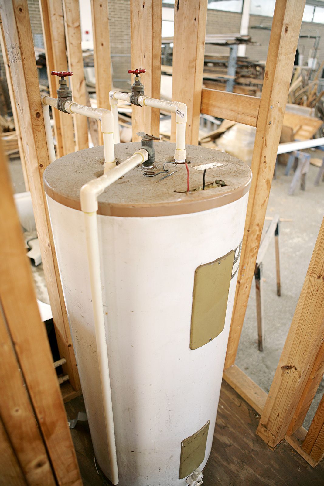 A water heater is sitting in a room under construction.