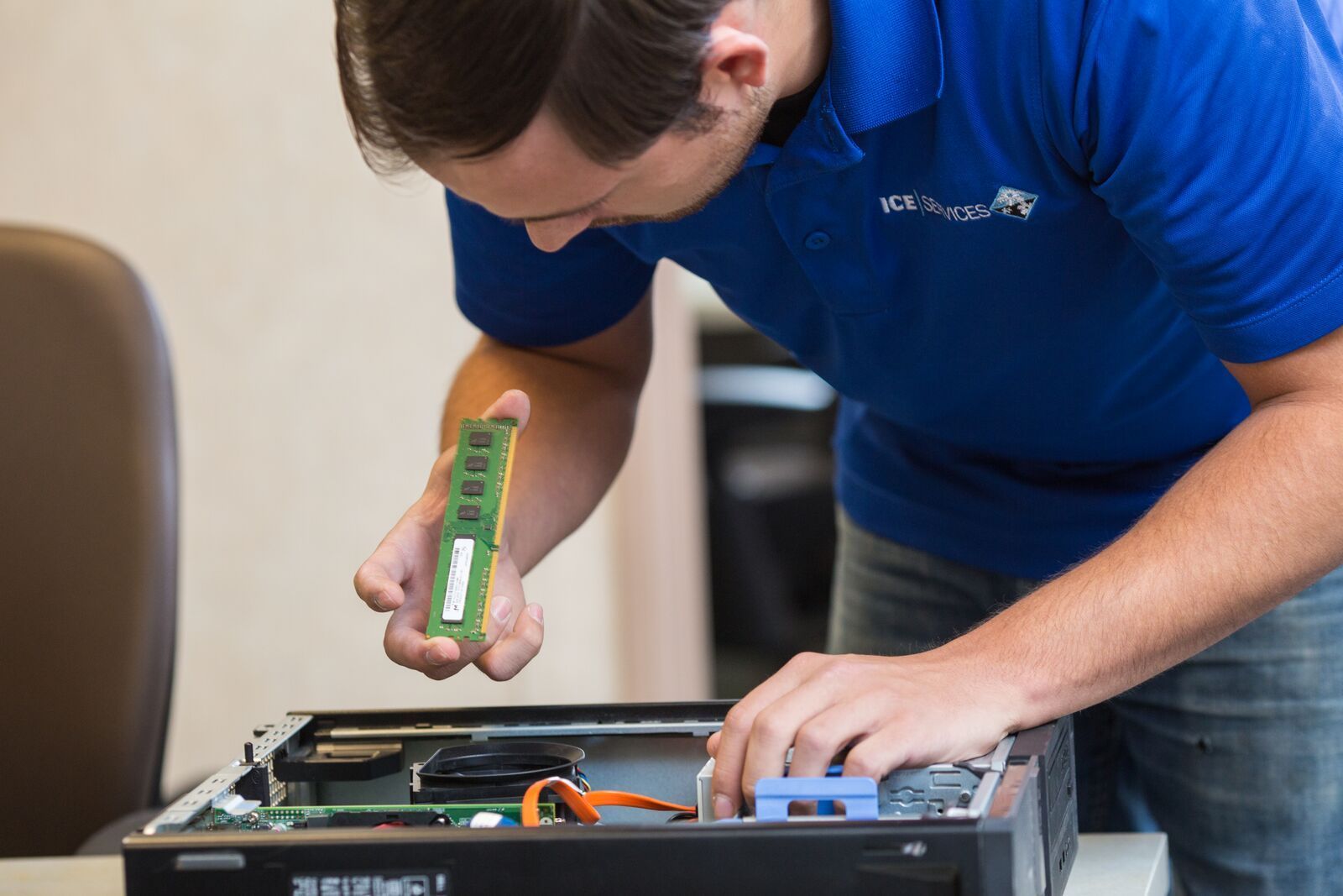A man in a blue shirt is working on a computer.
