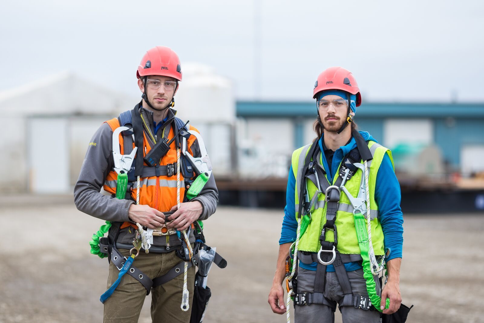 Two men wearing hard hats and safety vests are standing next to each other.