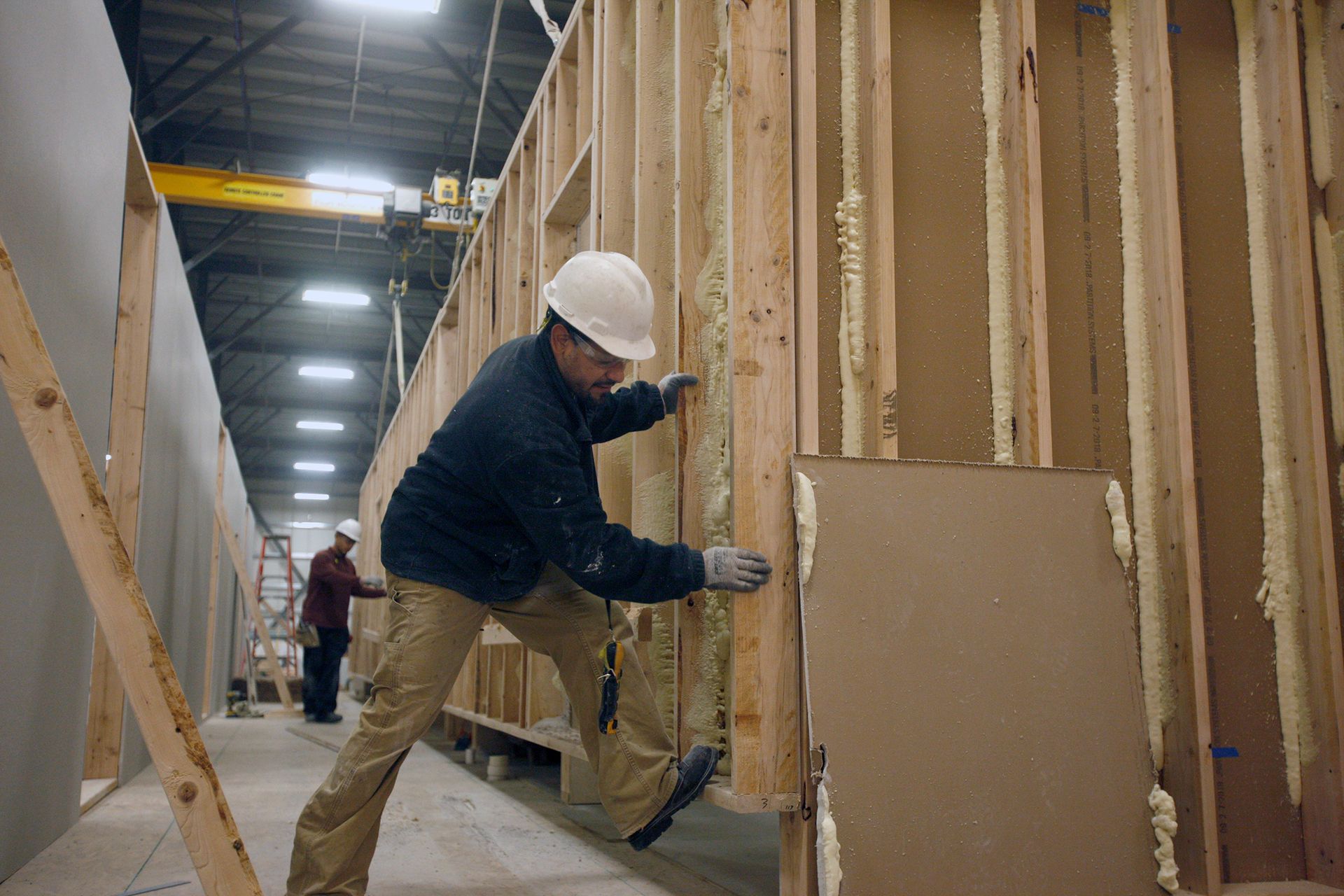 A man in a hard hat is working on a wooden wall.