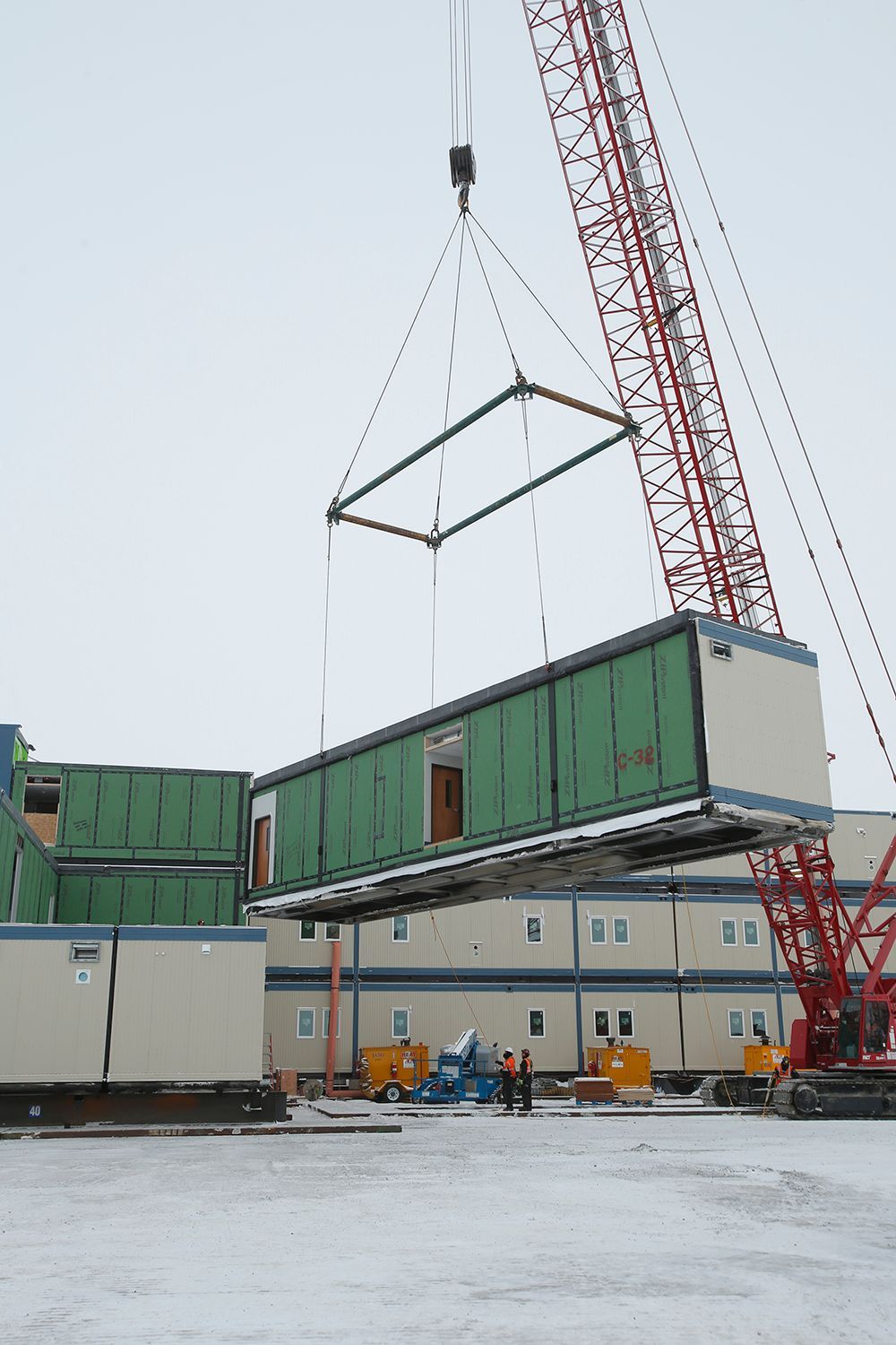 A crane is lifting a green and white building