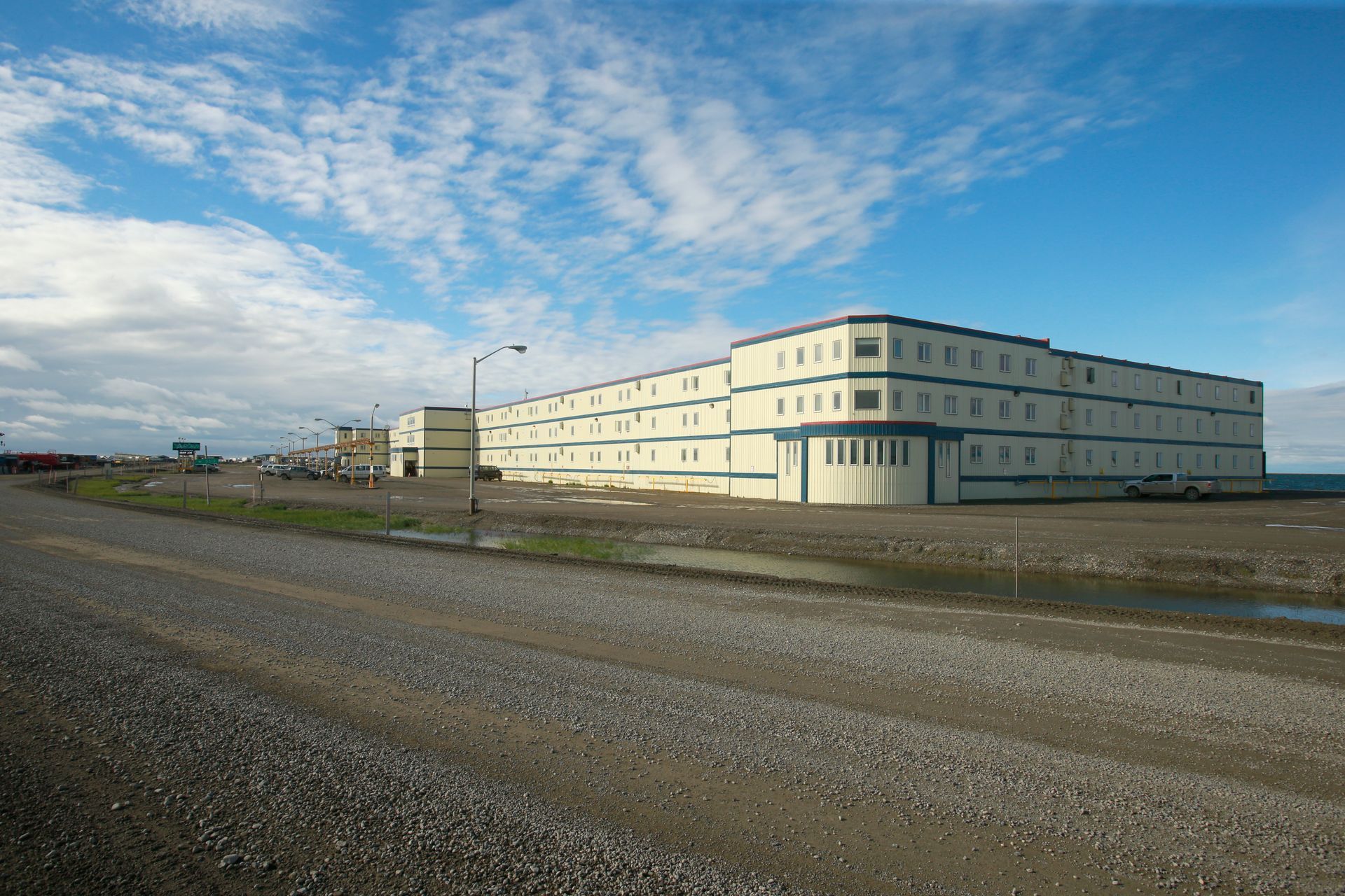A large building is sitting in the middle of a gravel road.