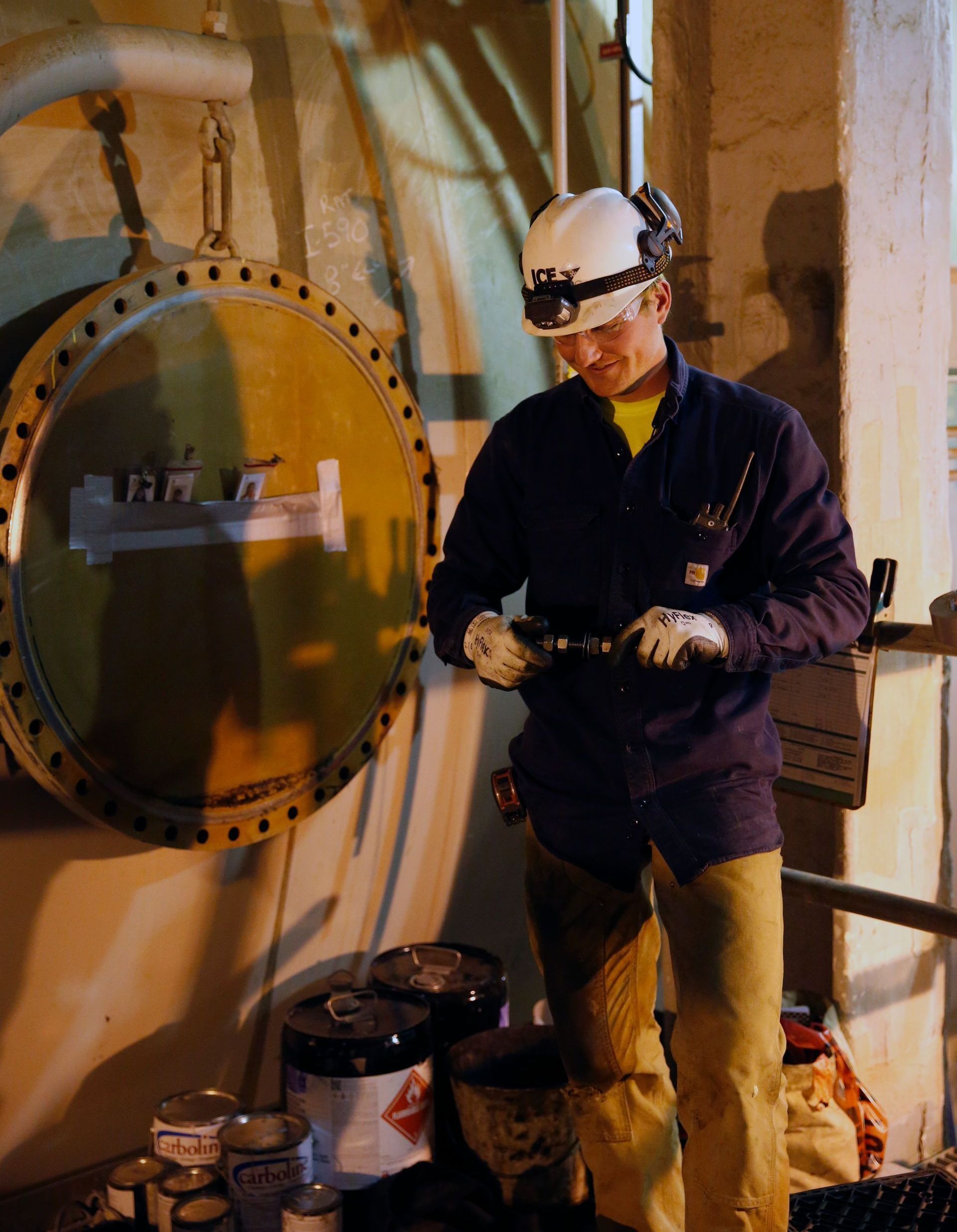 A man wearing a hard hat is looking at a tablet