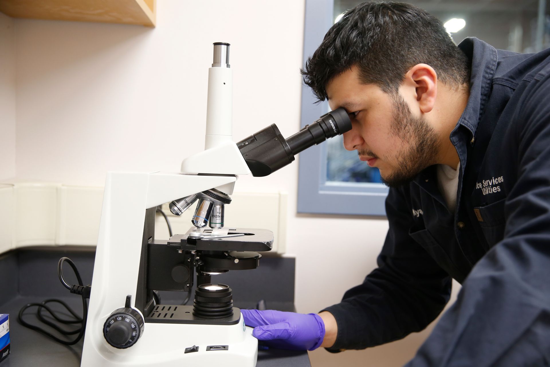 A man is looking through a microscope in a lab.
