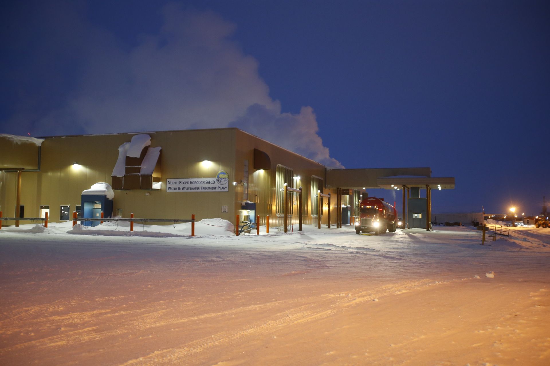 A truck is parked in front of a building in the snow.