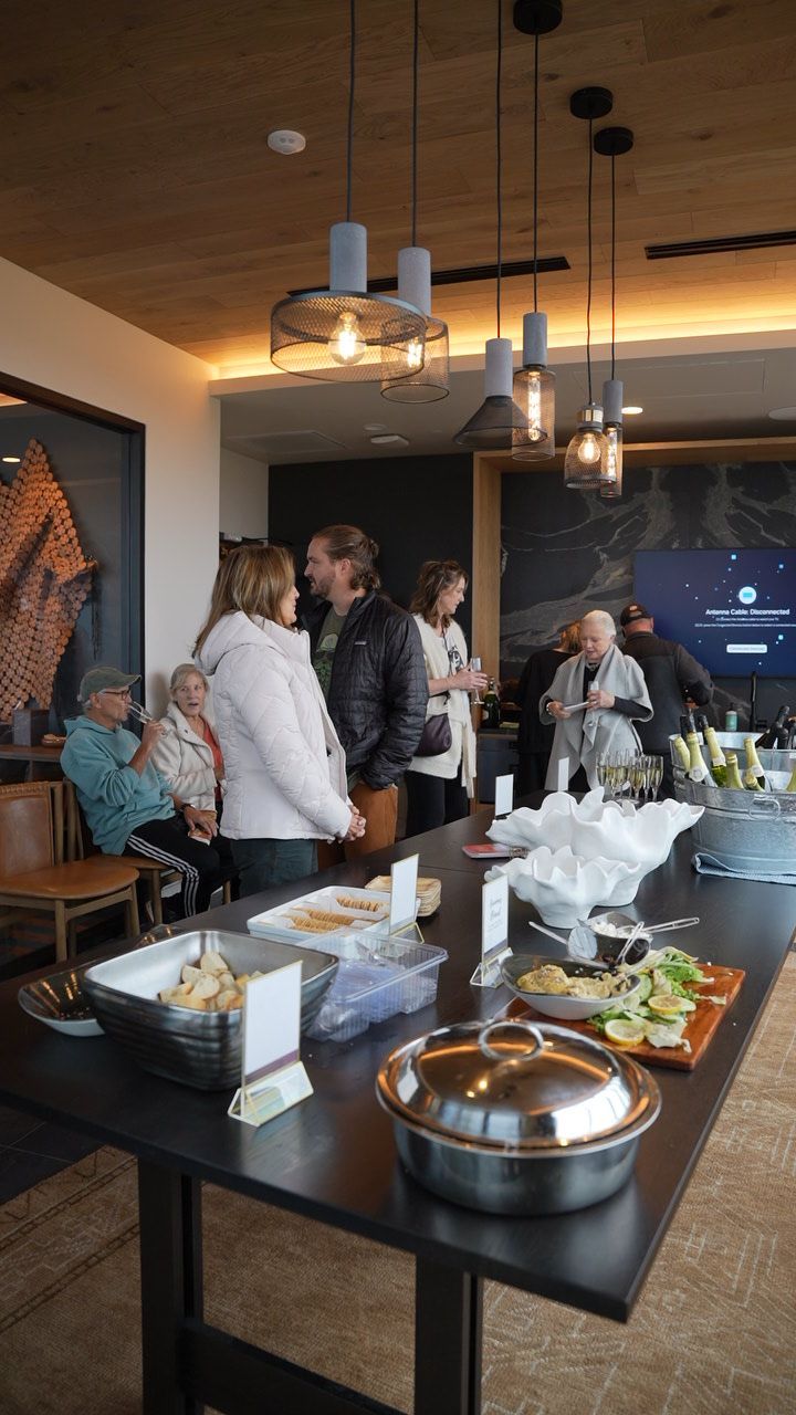 People at an event with food on a table, modern lighting, and art on the walls.