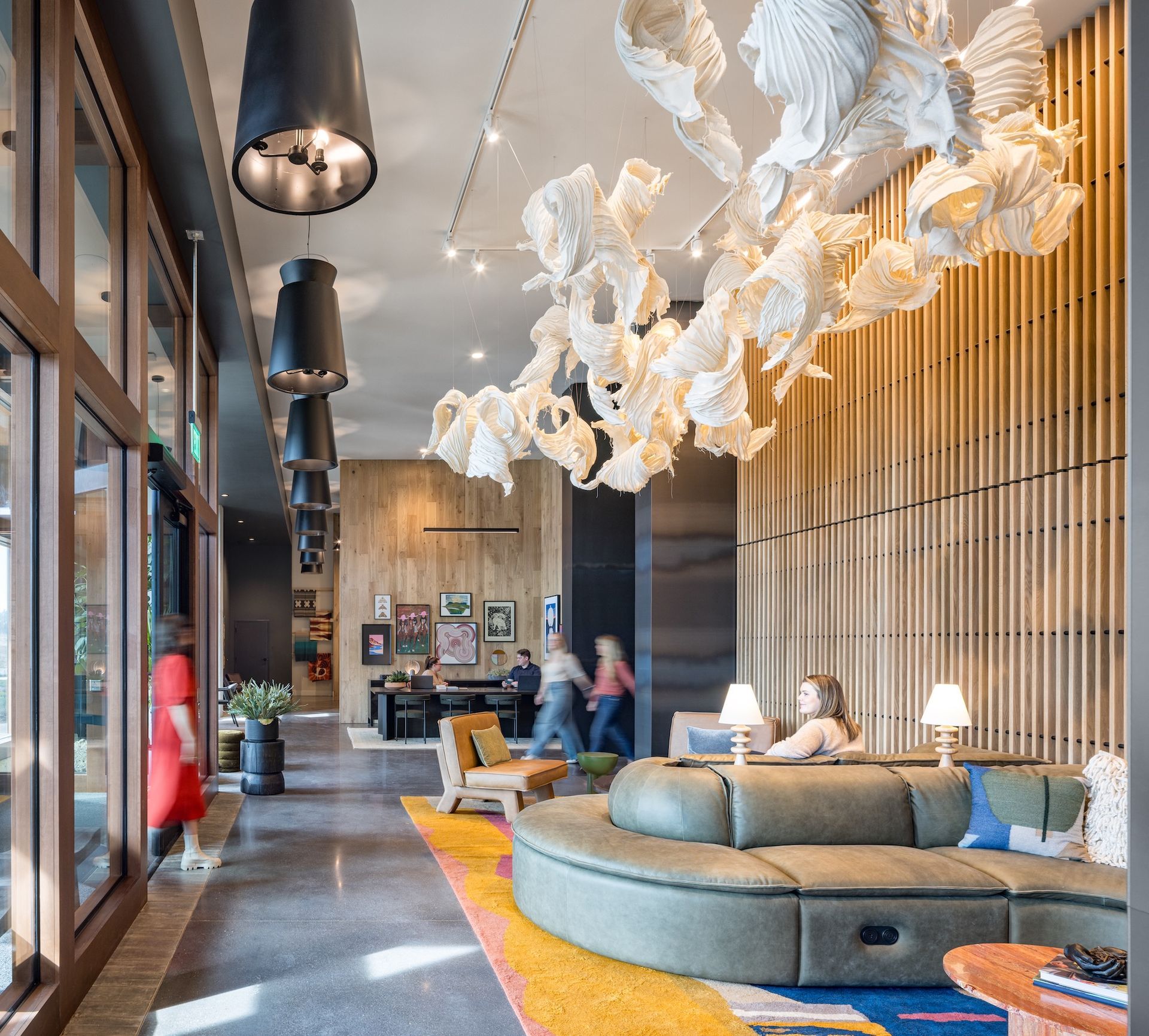 Hotel lobby with a curved sofa, artwork, and people walking.