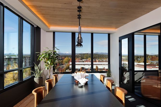 Meeting room with large windows, long table, leather chairs, and city view.