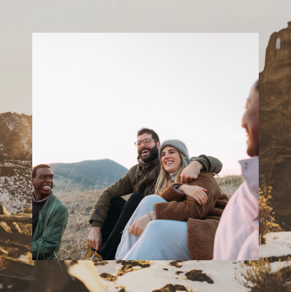 A group of people are sitting on a rock in a field.