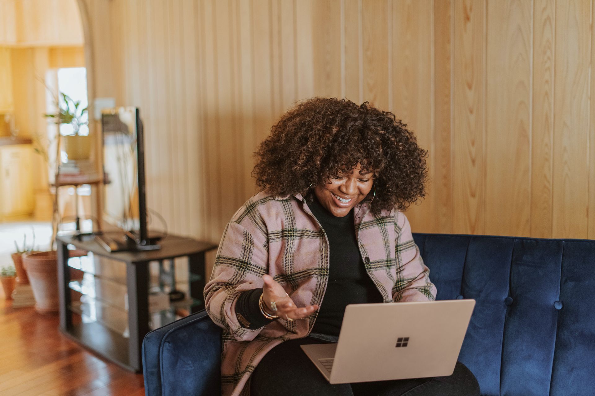 A woman is sitting on a couch using a laptop computer.