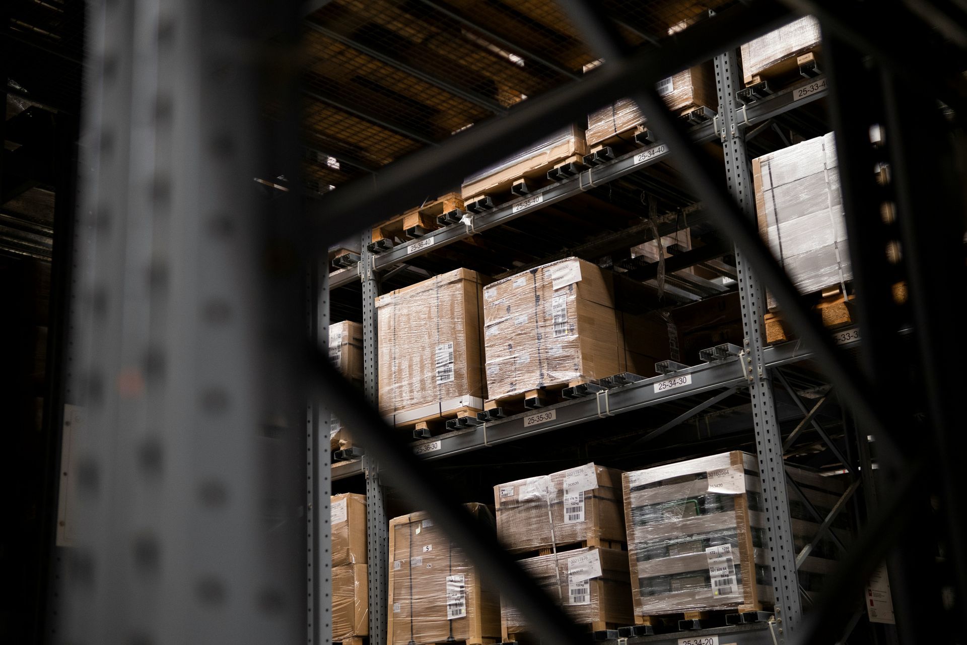 Warehouse shelving with stacked palletized boxes in a dim industrial storage area