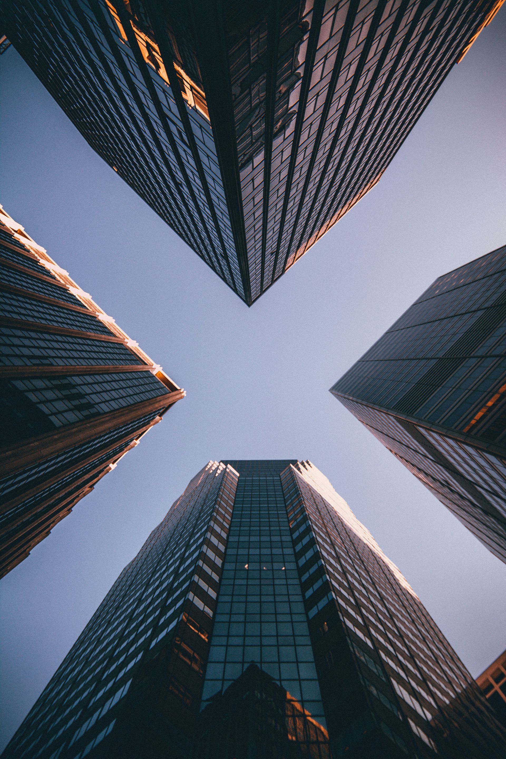 Four skyscrapers viewed from below against a dusky sky, forming a geometric frame.