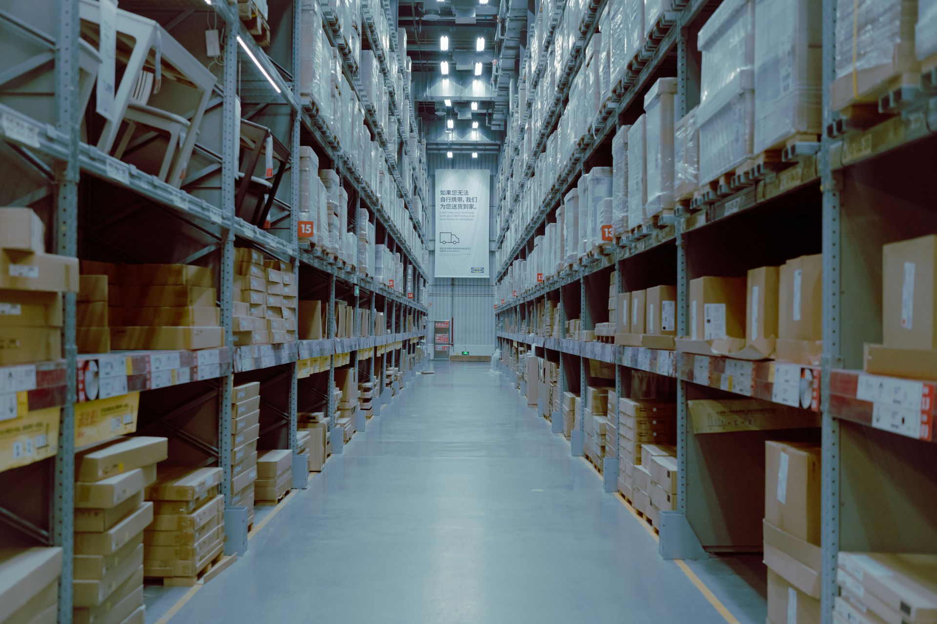 A warehouse aisle with tall metal shelves stacked with boxes and packages.