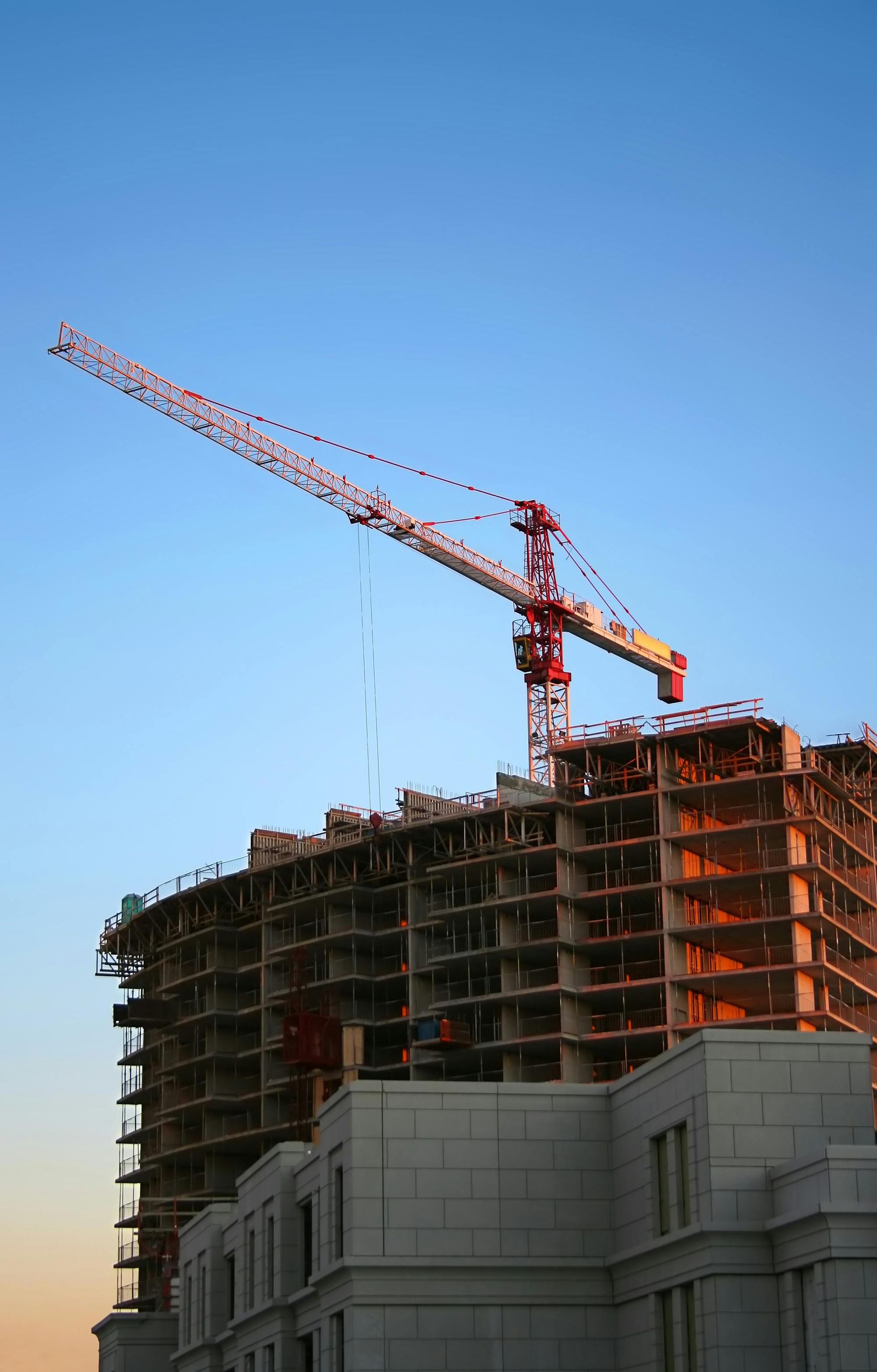 Crane atop a high-rise construction site against a clear blue sky