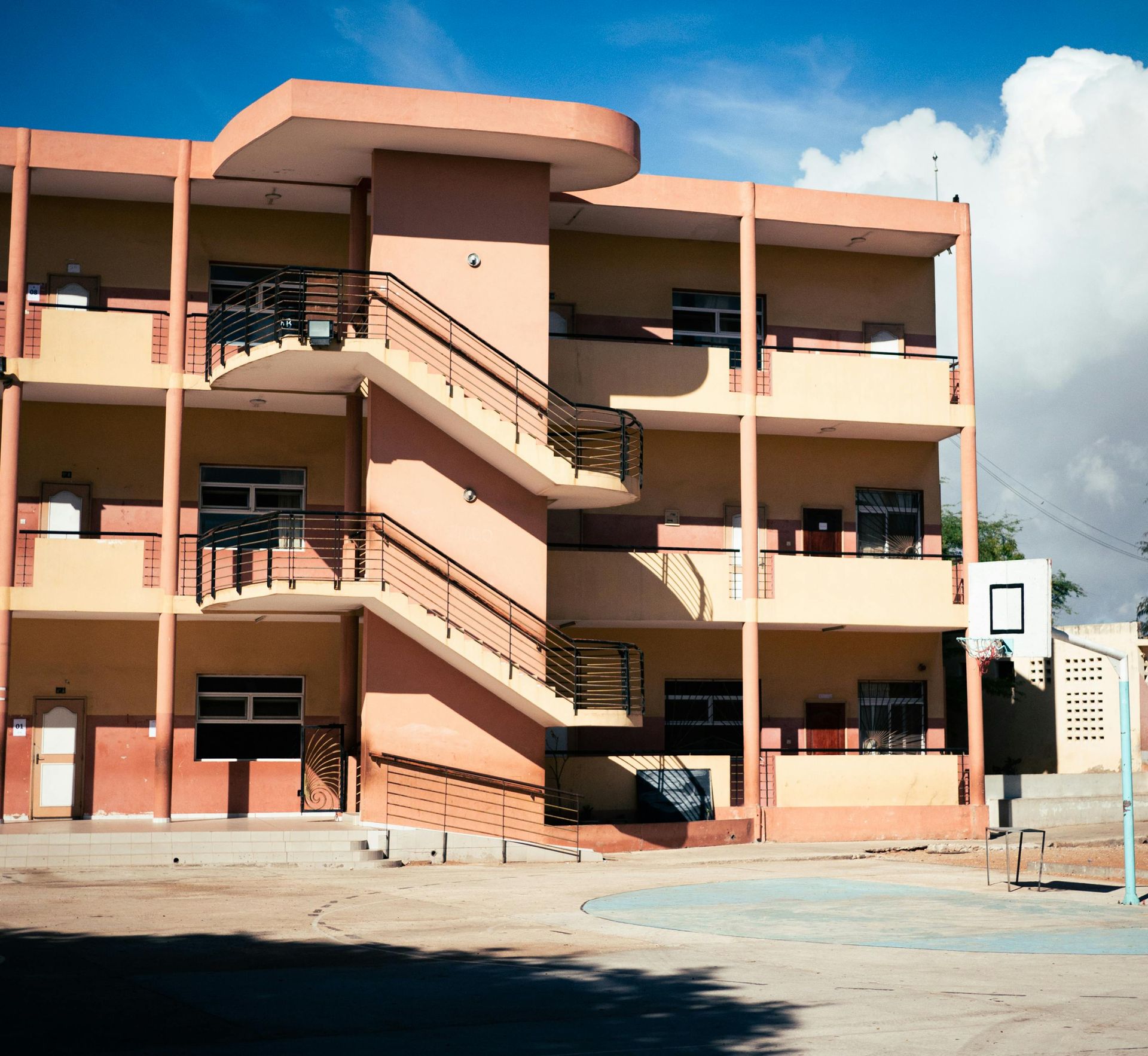 Three-story beige apartment building with exterior staircases under a blue sky