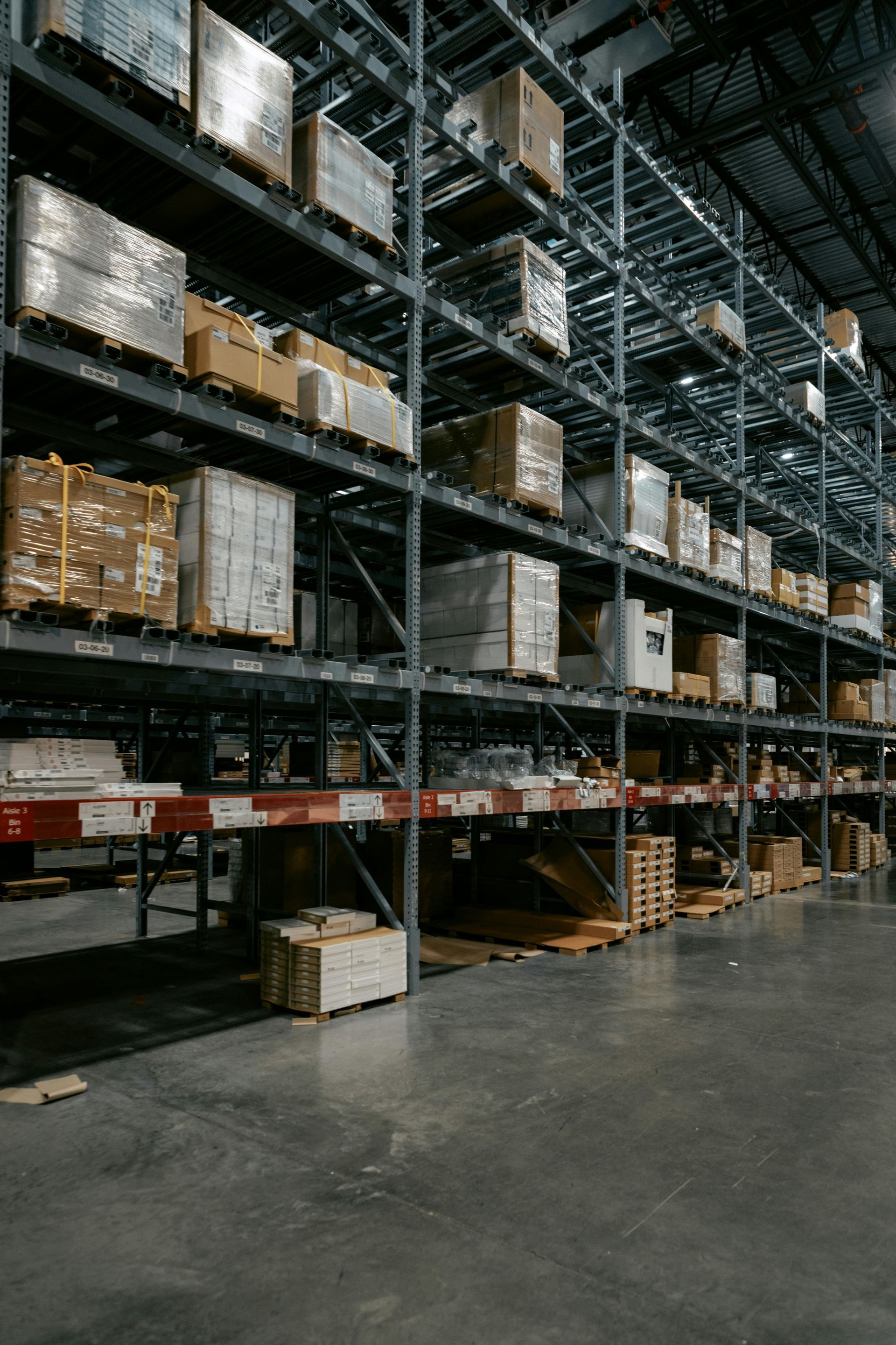 Warehouse aisles with stacked pallets and boxes on tall metal shelving