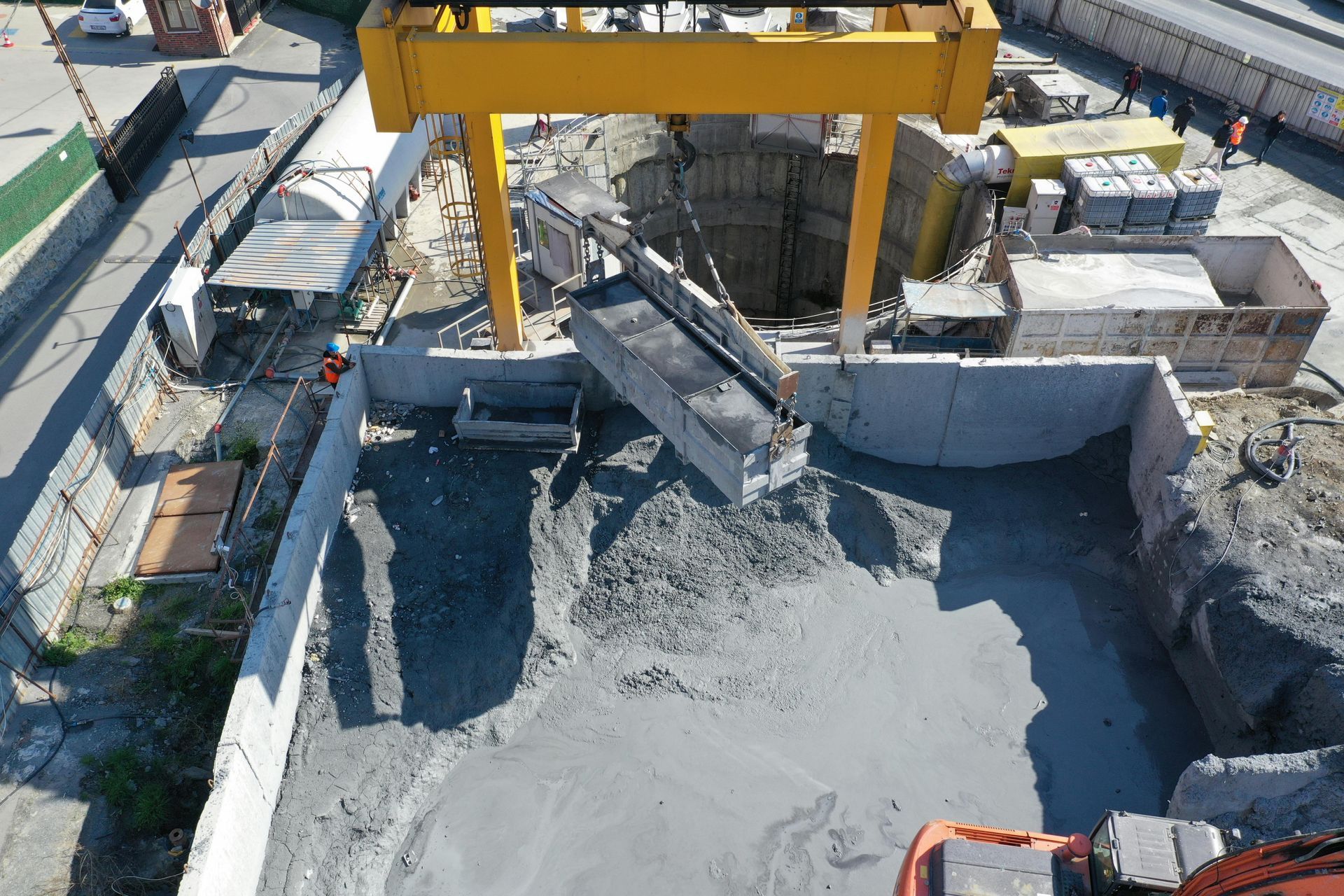 Construction site with a yellow crane pouring concrete into a foundation pit