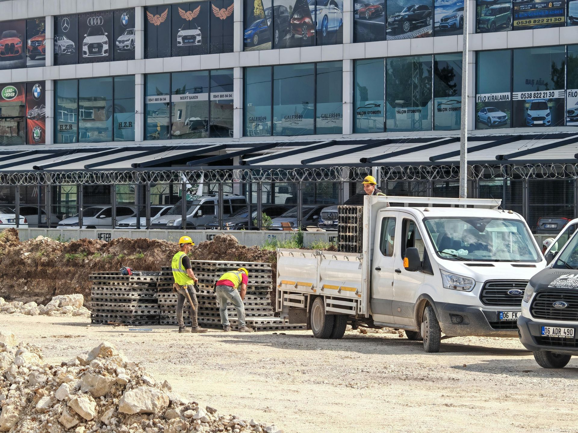 Workers and a white utility truck at a construction site in front of a modern building