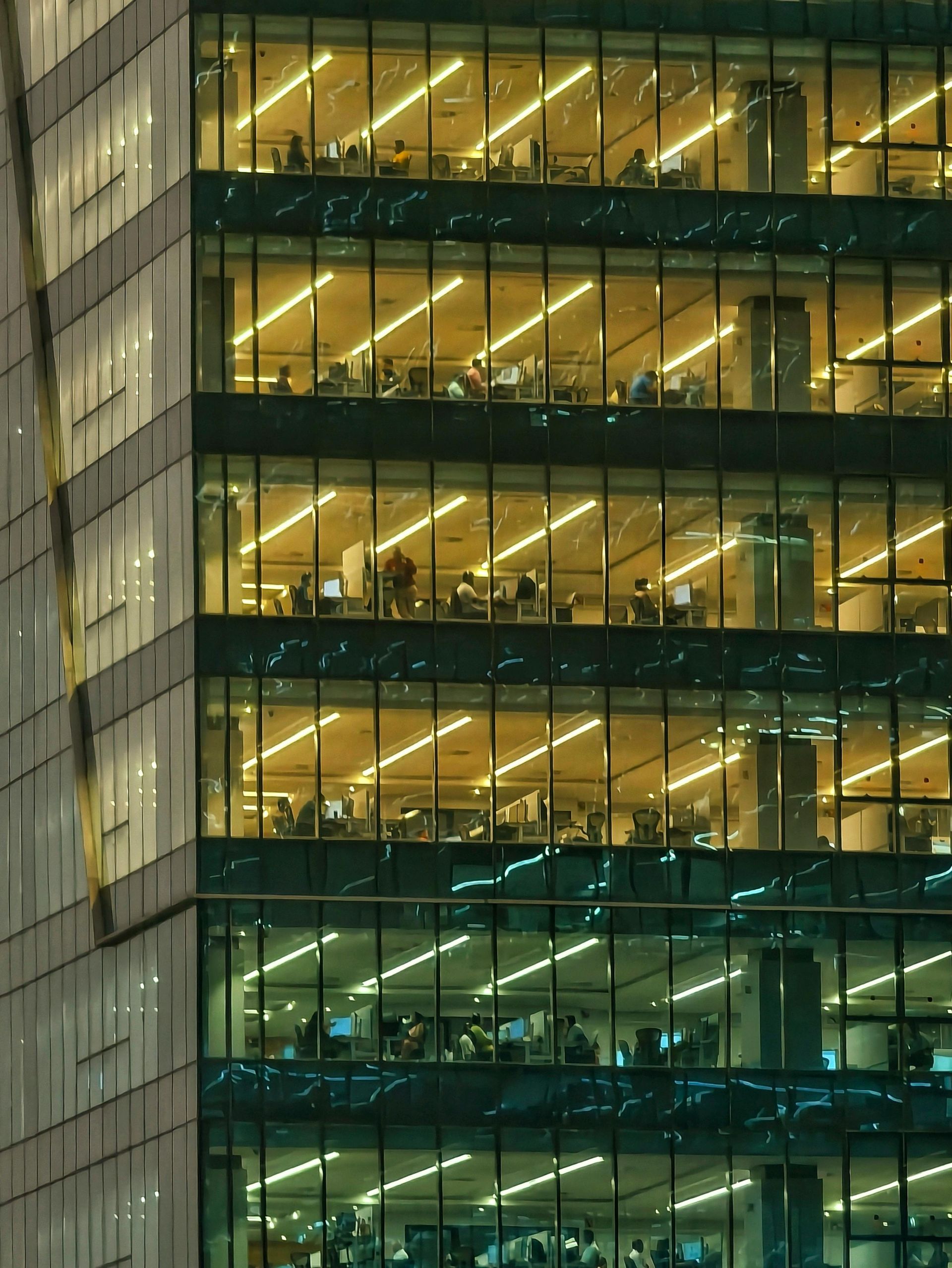 Lit office windows in a modern glass building at night