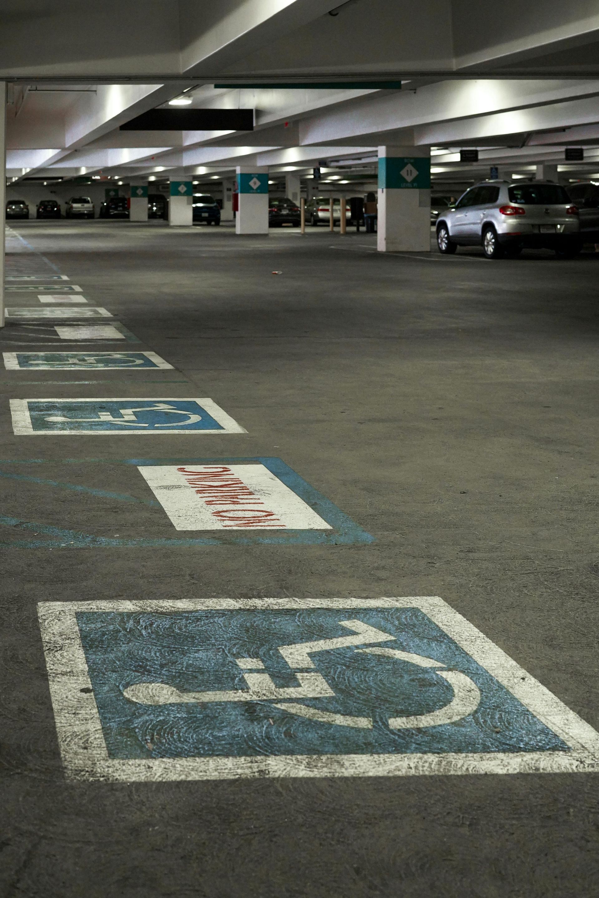 Empty parking garage with marked handicapped parking spaces and a few cars in the distance