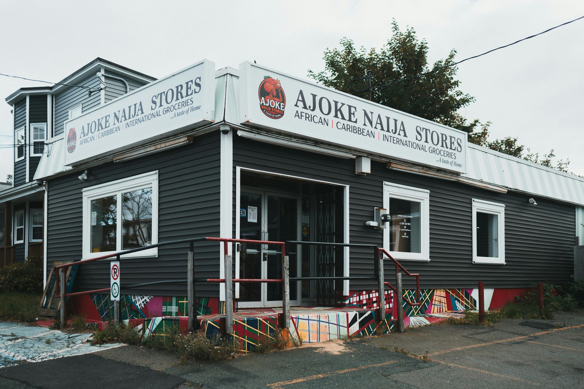 Exterior of A Joke Nia Store, a dark building with white signage and colorful decorations outside