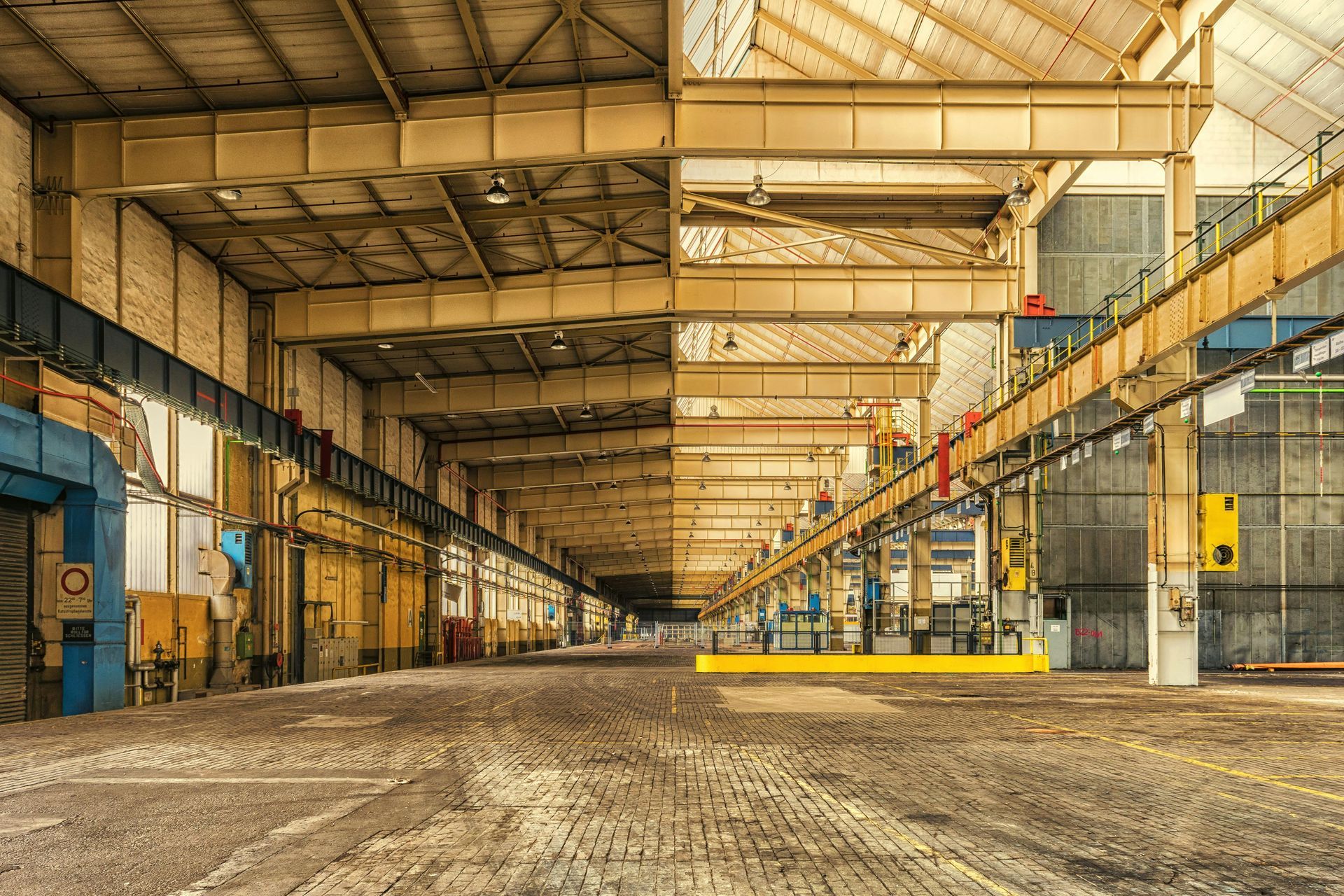 Empty industrial warehouse interior with yellow steel beams and a dirt floor