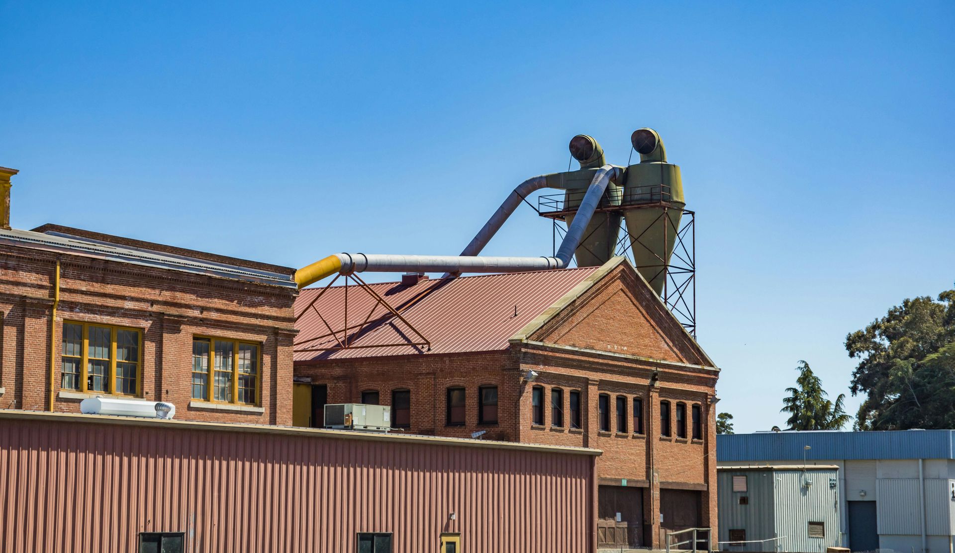 Workers on a rooftop repairing a brick building under a clear blue sky