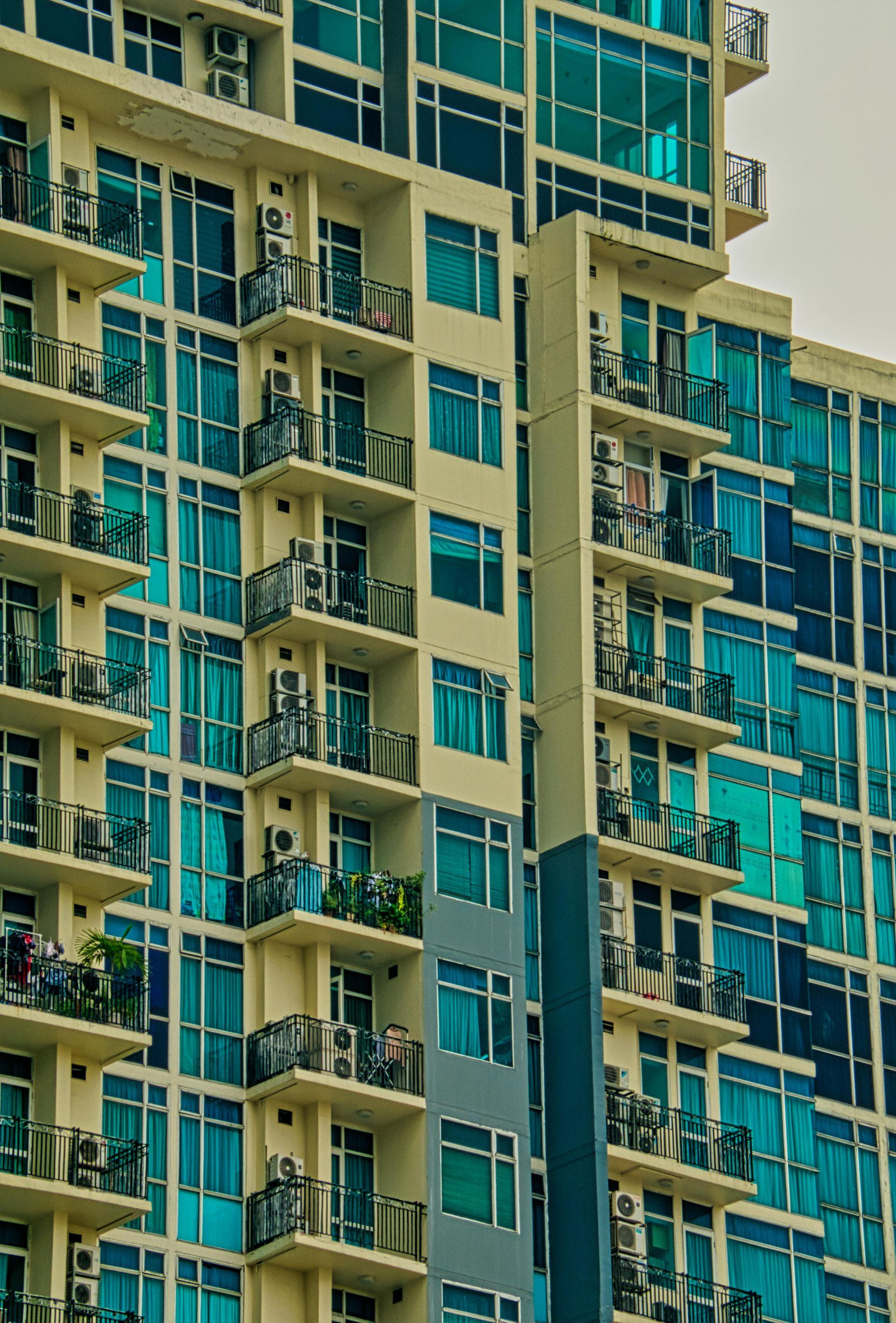 High-rise apartment balconies with teal windows and beige walls