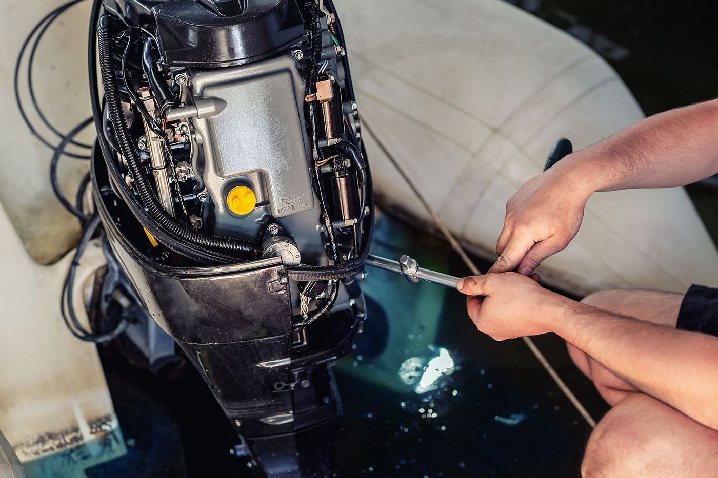 A man is working on an outboard motor on a boat.