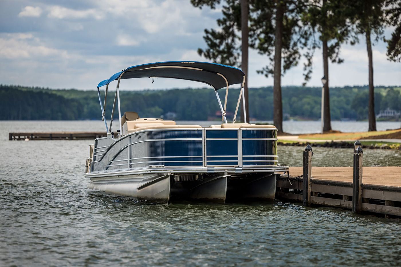 A pontoon boat is docked at a dock on a lake.