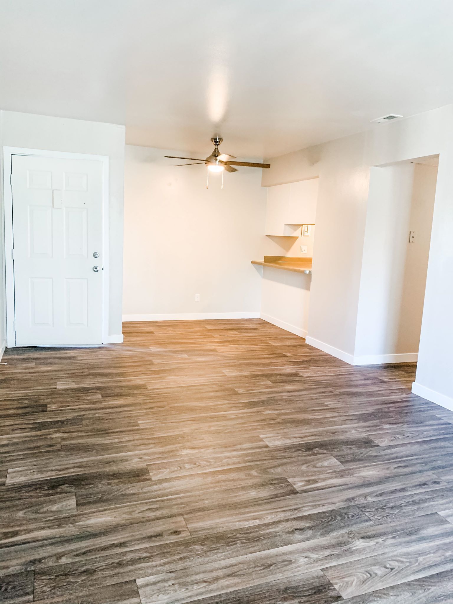an empty living room with wooden floors and a ceiling fan .