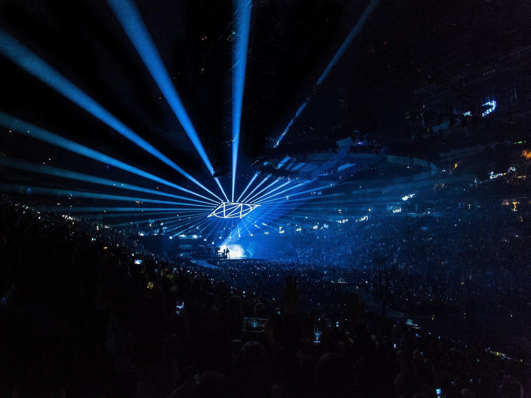 a crowd watching a concert with blue lights coming out of the ceiling